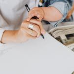 Close-up of a parent and child writing on paper together indoors, showcasing bonding and creativity.